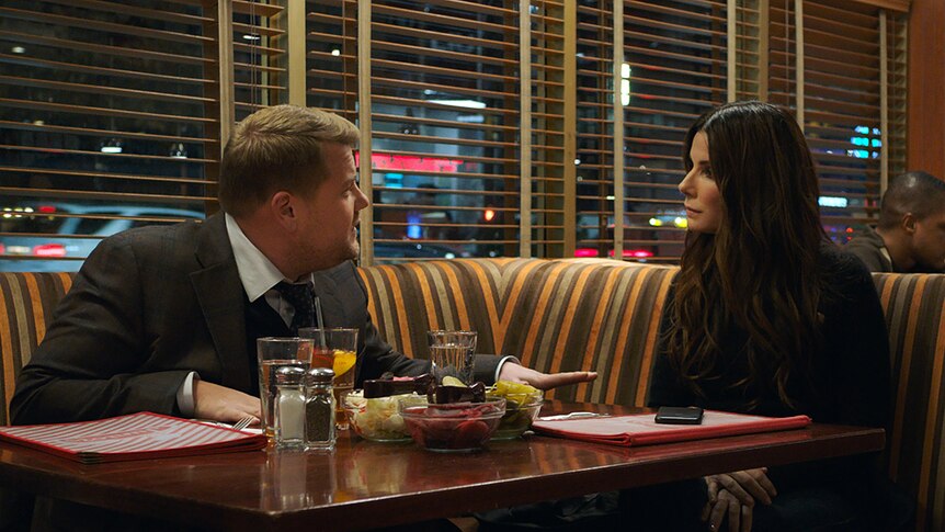 Colour photograph of James Corden and Sandra Bullocksitting at a diner booth at night time in 2018 film Ocean's 8.