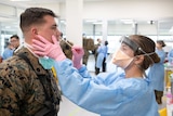 A US Marine is screened for coronavirus as a nurse takes a nose swab.