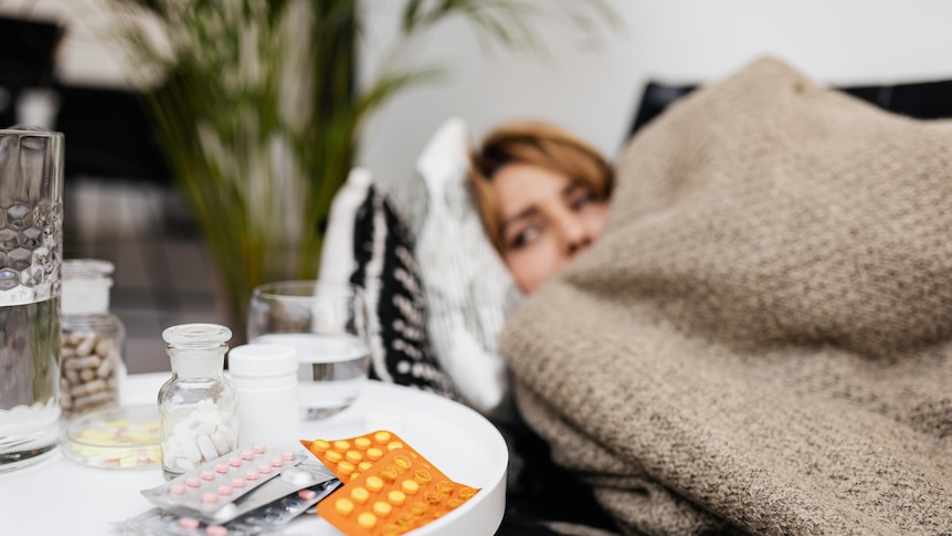A woman lying in bed with medications next to her