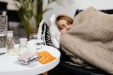 A woman lying in bed with medications next to her