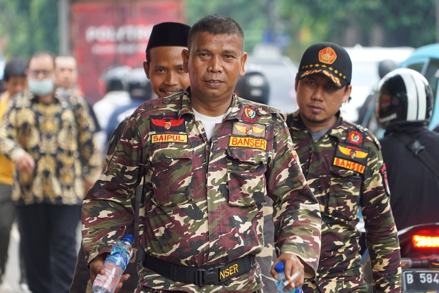 Three men in camo gear walking down a street in Jakarta