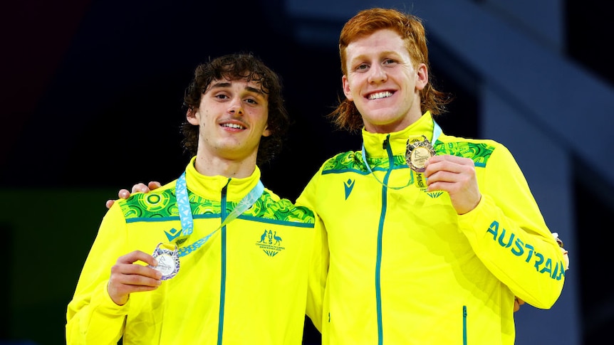 Two Australian para-athletes pose with gold and silver medals.