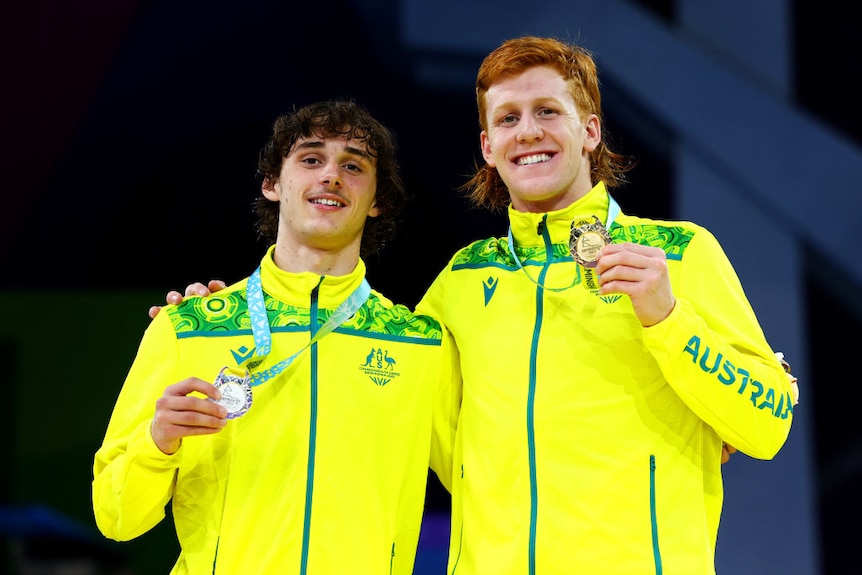 Two Australian para-athletes pose with gold and silver medals.