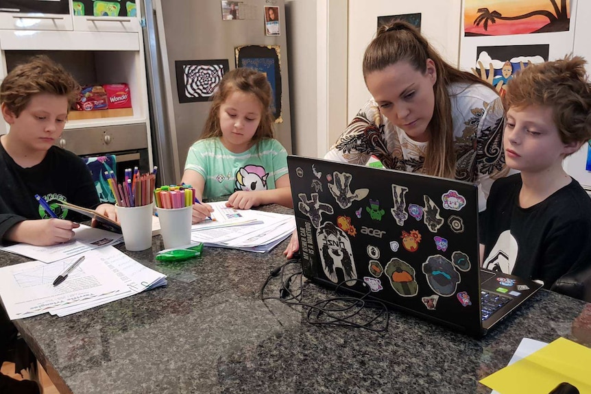 Charlotte Smith with children Brandon, Celestia and Haru who are doing school work a table.