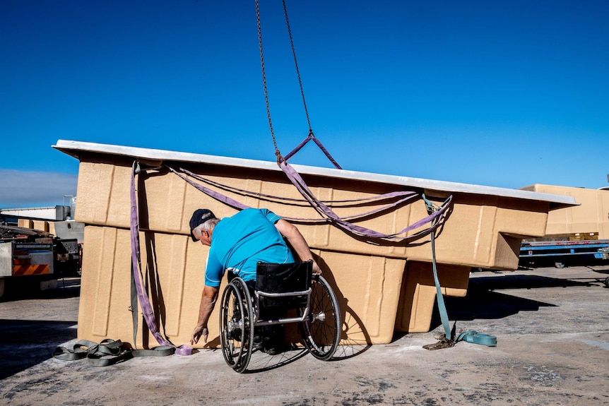 Andrew in an wheelchair helping load up a pool on to a crane.