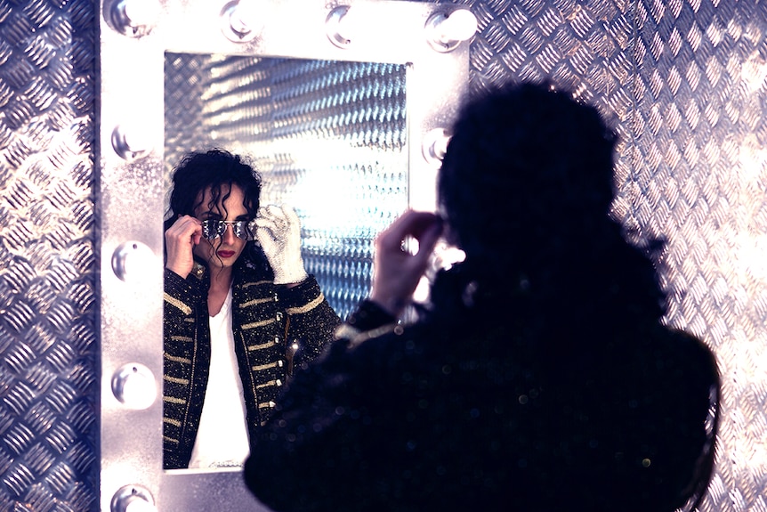A Michael Jackson impersonator looks in the mirror.