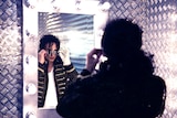 A Michael Jackson impersonator looks in the mirror.