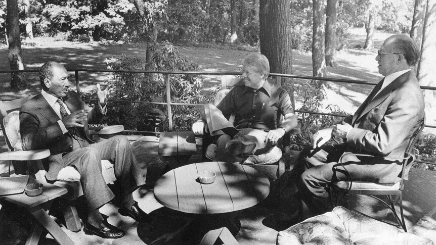 Anwar El Sadat, Jimmy Carter and Menachem Begin sit around an outdoor table at Camp David.