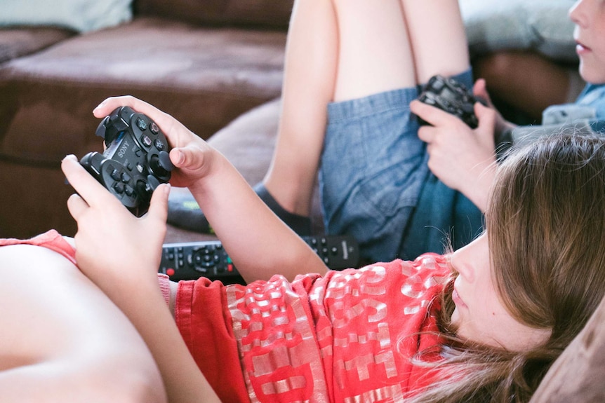 Two young kids, not showing their faces, playing video games to demonstrate how to teach kids to be good losers and winners.