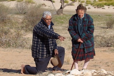 A man and a woman in the desert pointing at a site.