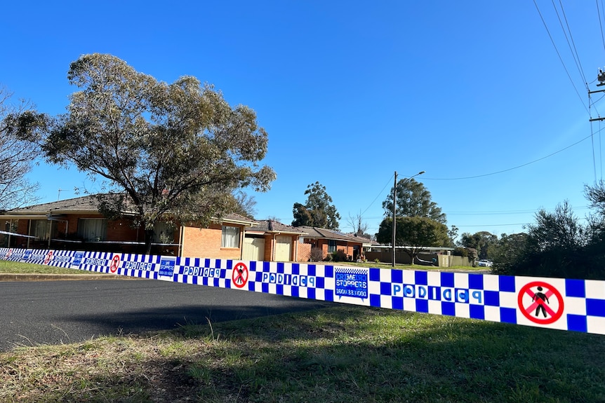 Police tap surrounding a red brick house in Dubbo