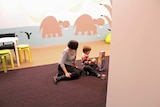 A woman and child play in a room decorated with pastel coloured hippos