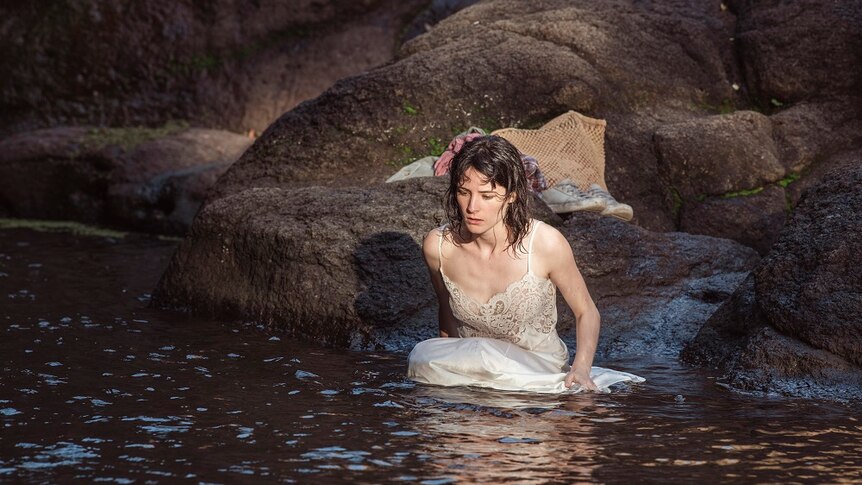 Lead actress in petticoat wading into rainforest pool