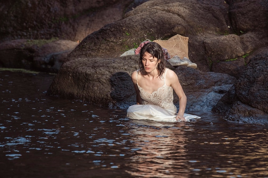Lead actress in petticoat wading into rainforest pool