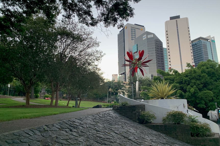 A park with green lawn and a few sky scrapers in the background.