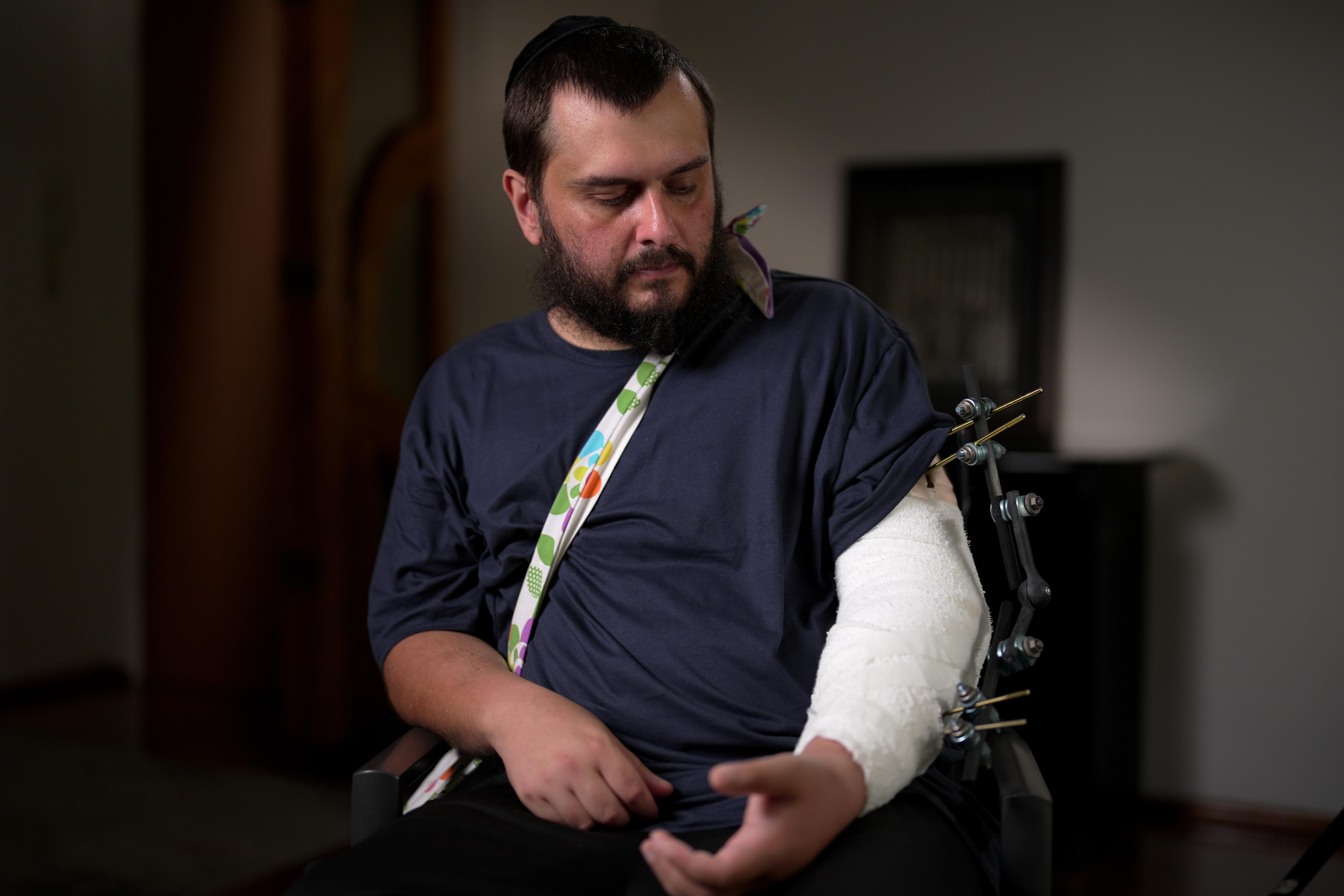 Uma vítima de tiroteio em Bondi olha para seu braço em uma tipóia.