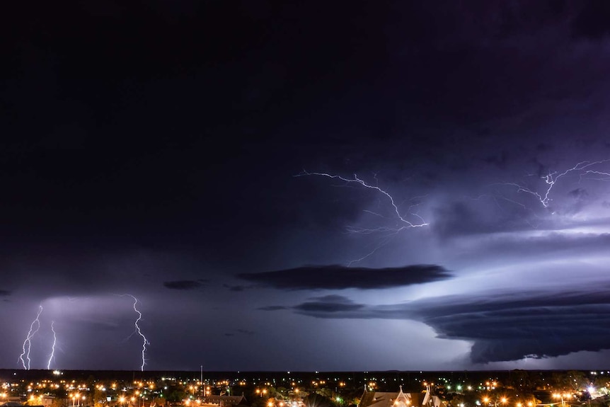 Dark clouds and lightning at night, over a regional town.