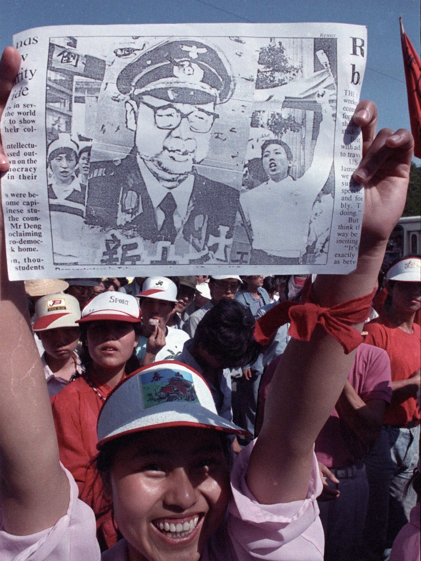 A film photo shows a student protestor holding up a caricature of Chinese Premier Li Peng in Nazi uniform.