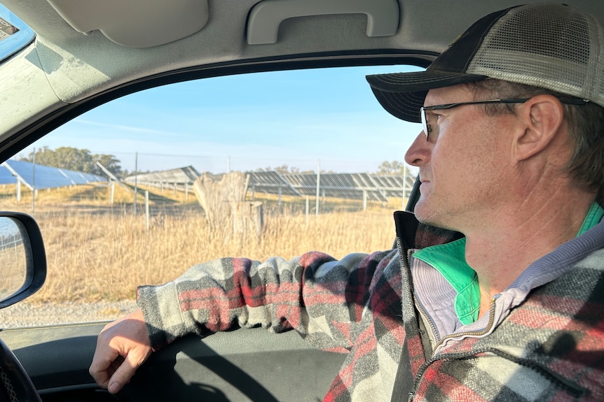 Male farmer sitting in utility looking out at solar development