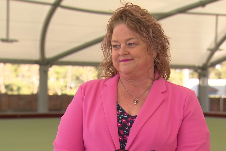 A woman in a pink blazer smiling at a bowling club