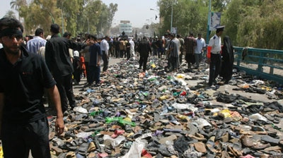 Iraqi pilgrims walk past shoes lost during the stampede.