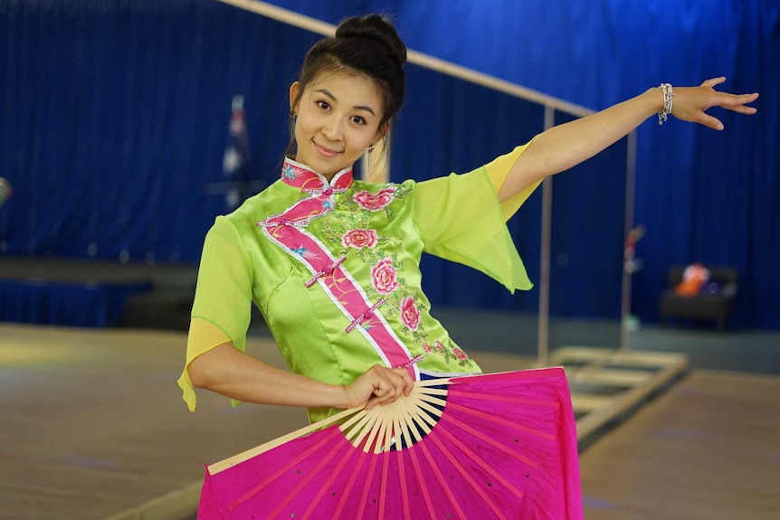 Chinese migrant Eva Zhang poses in green dress and carry a red fan.