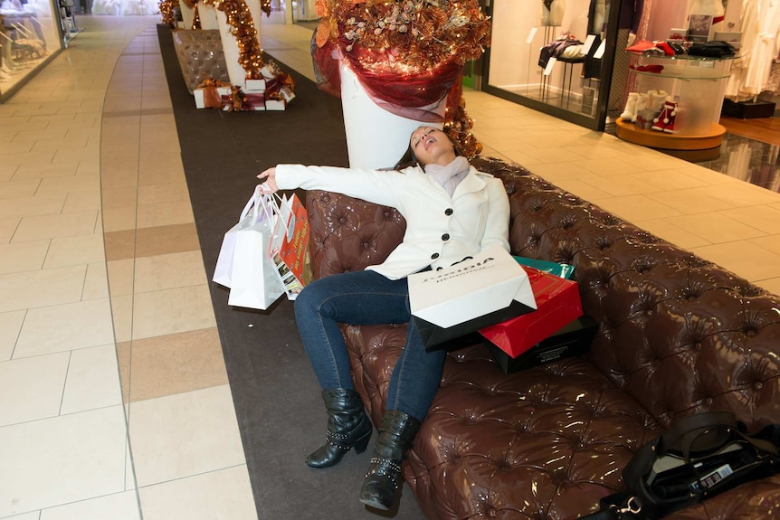 A tired woman with shopping bags lying on a couch