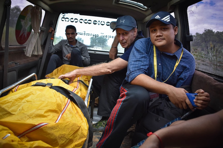 three men in the back of a burmese ambulance