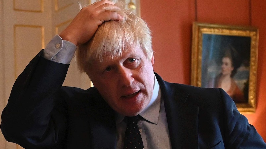 Boris Johnson, looking concerned, runs a hand through his hair.