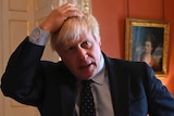 Boris Johnson, looking concerned, runs a hand through his hair.