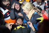 Teenager surrounded by rescuers and his mum after being pulled out from under rubble.
