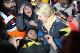 Teenager surrounded by rescuers and his mum after being pulled out from under rubble.