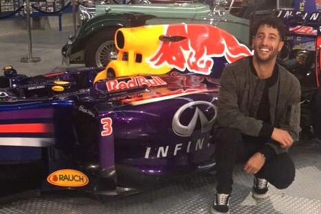 Australian Formula One driver Danial Ricciardo kneels next to an F1 car.
