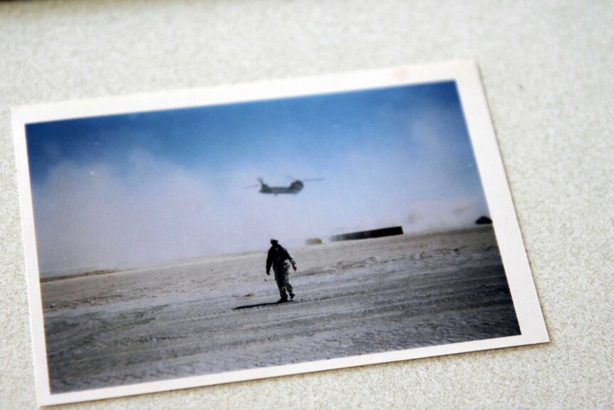 A soldier walking across a battlefield.