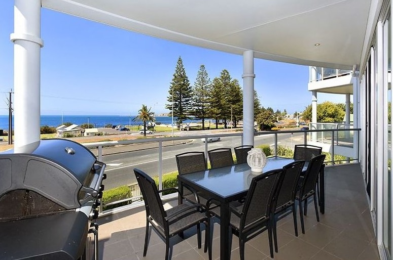 The view from an apartment balcony overlooking the ocean.