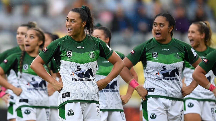 Several Māori Ferns players perform the haka, standing with their hands on their hips