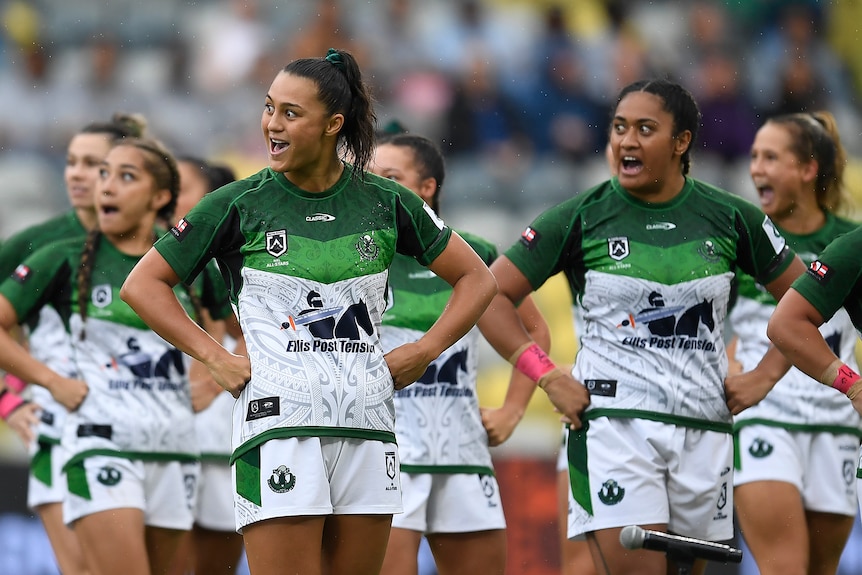 Several Māori Ferns players perform the haka, standing with their hands on their hips