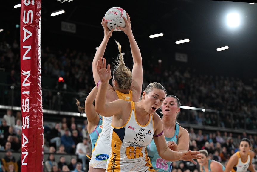 Bruce loses her balance as her teammate Hinchliffe holds onto the rebound and a high stand full of fans watches on