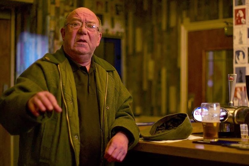 Man in a pub next to a cap and a beer.