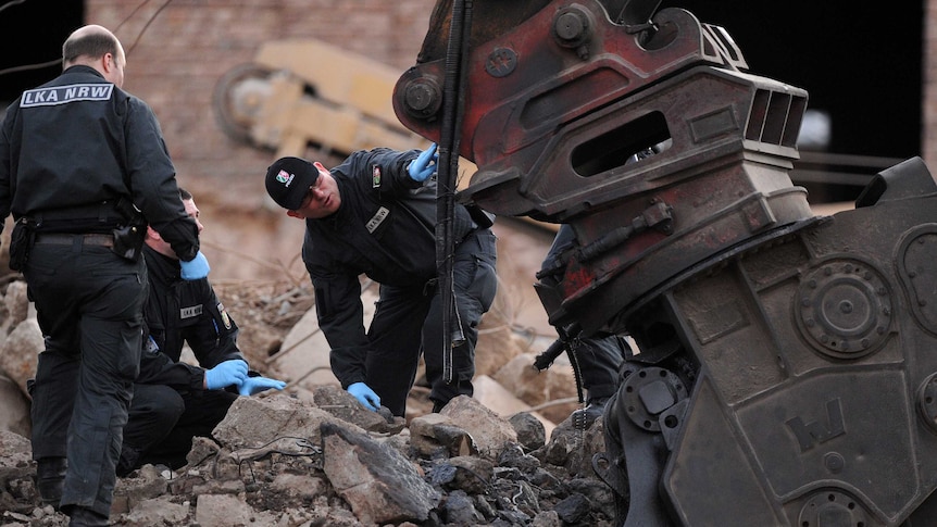 Officers examine a damaged excavator at the accident site of an exploded WWII bomb in Euskirchen
