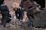 Officers examine a damaged excavator at the accident site of an exploded WWII bomb in Euskirchen
