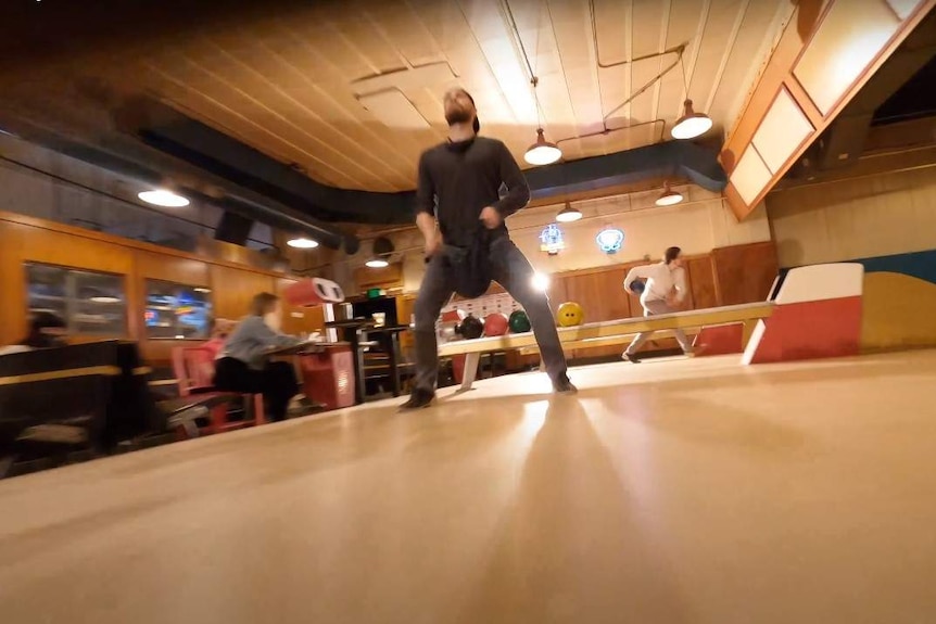 A man cleans a bowling ball in a bowling alley.