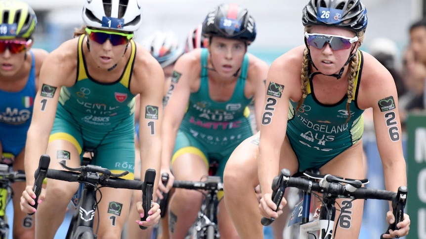 Ash Gentle and Jaz Hedgeland ride side by side in a triathlon race