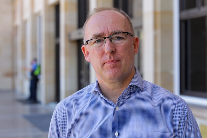 A mid shot of a man wearing glasses with a concerned look on his face