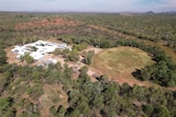 a drone image of a group of white building and a football oval surrounded by trees