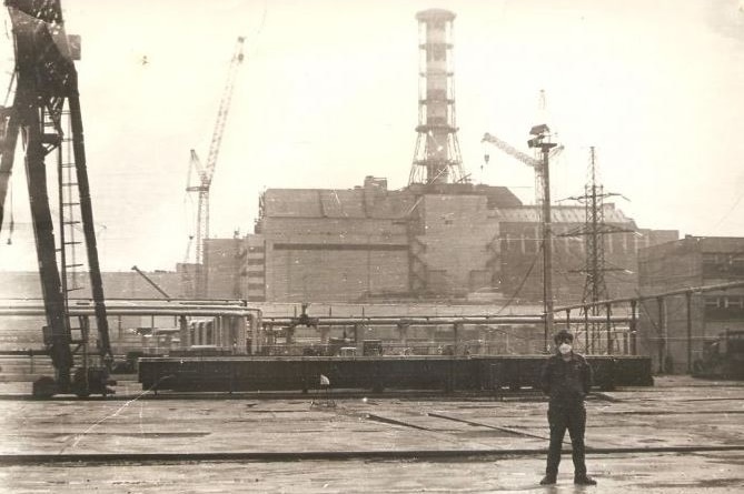 A man standing next to Chernobyl sarcophagus.