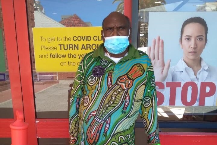 A man standing in front of a hospital. 
