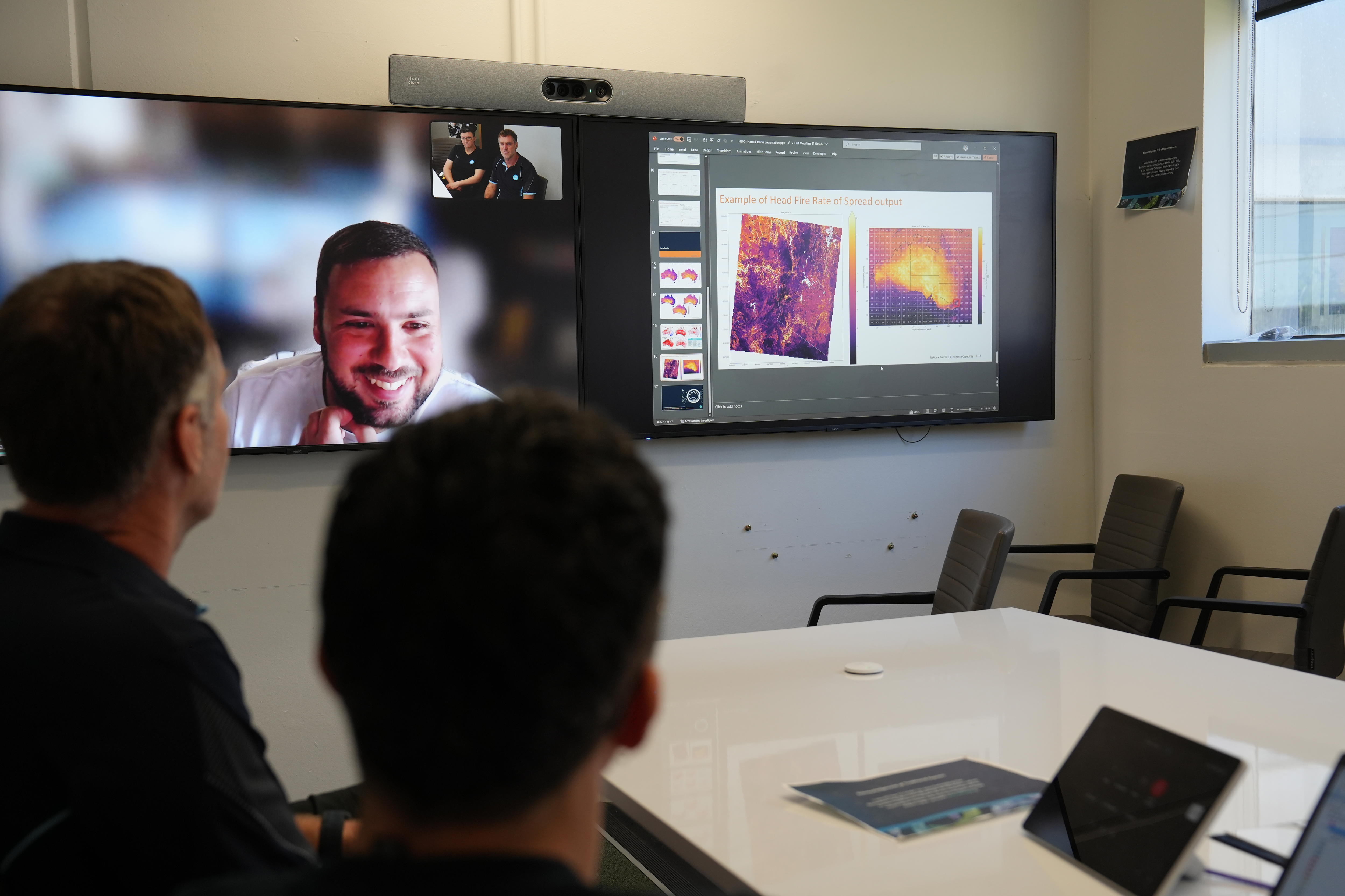 Two people in a room and another person on zoom looking at a powerpoint with a map of Australia.