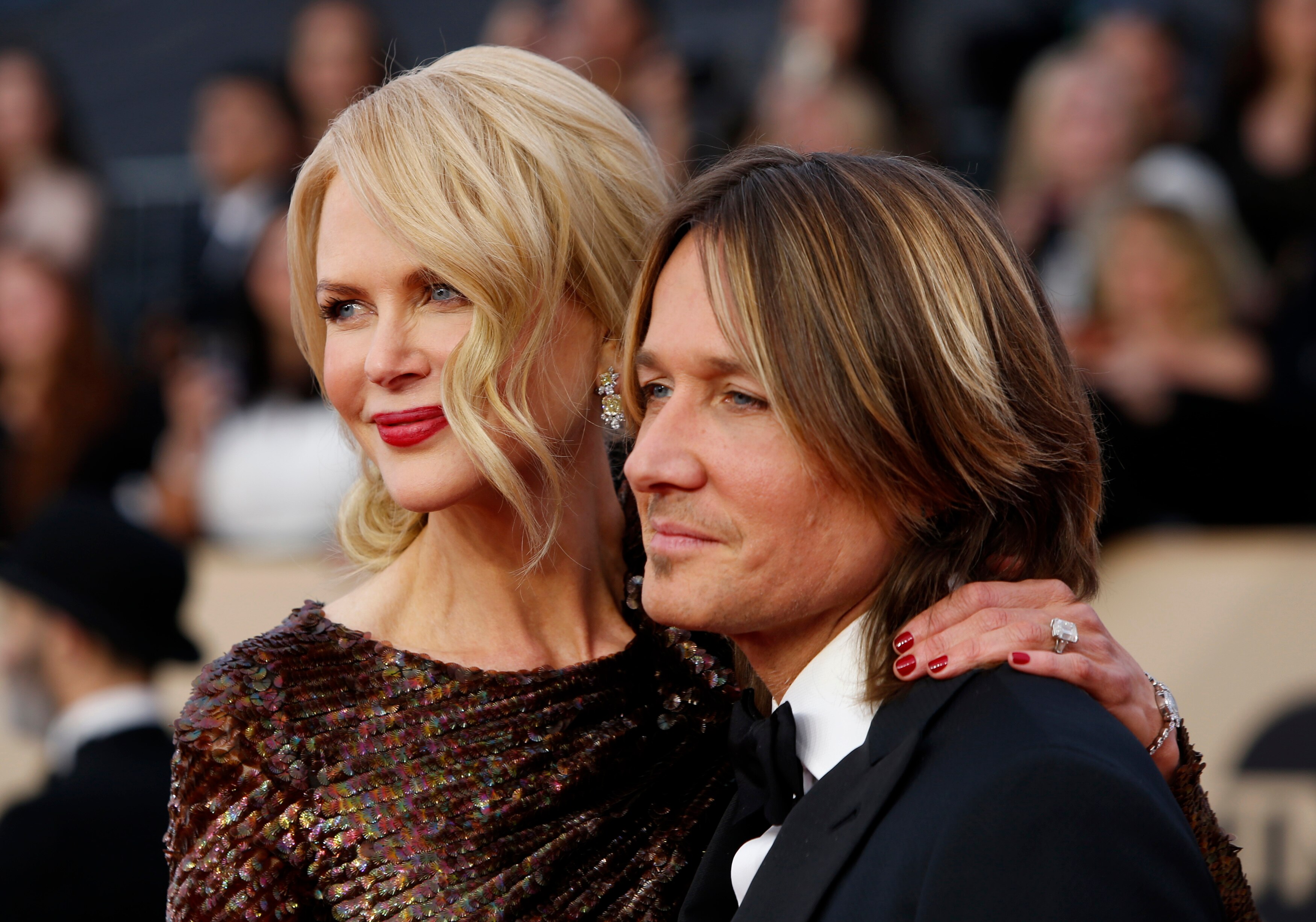 A couple smiles and poses cheek to cheek. 