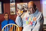 Bill Cosby holds a shot glass and screws up his face during a performance.